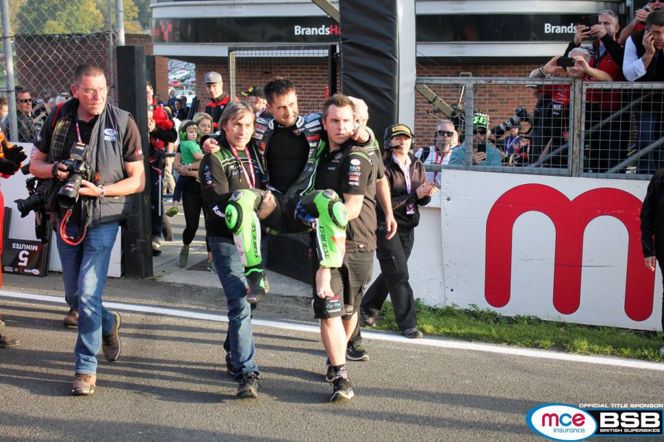 Отец, Рон Хезлам и менеджер команды JG Speedfit Kawasaki помогают Леону добраться до закрытого парка Отец, Рон Хезлам и менеджер команды JG Speedfit Kawasaki помогают Леону добраться до закрытого парка